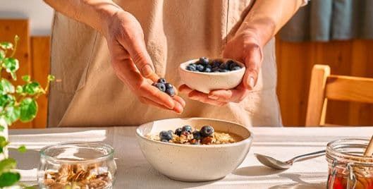 Person preparing a healthy bowl of fruit and whole grains